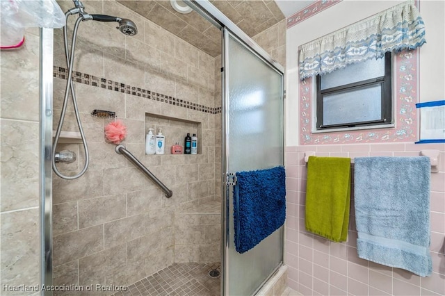 bathroom with an enclosed shower and tile walls