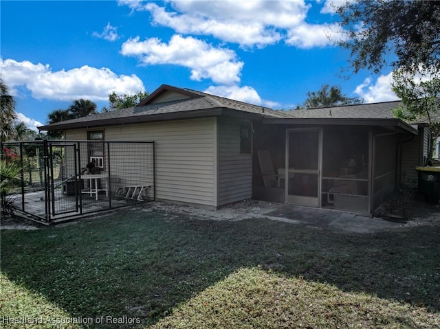 back of property featuring a lawn, a sunroom, and a patio