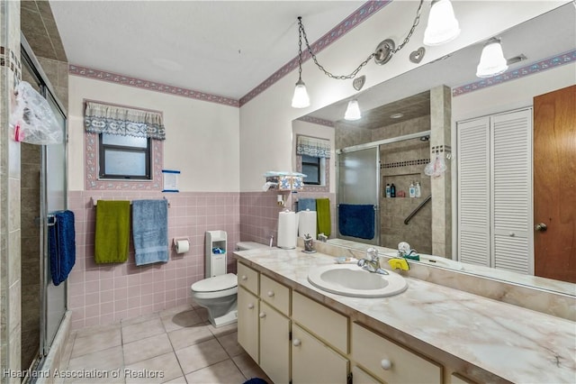 bathroom featuring tile patterned flooring, vanity, a shower with door, and tile walls