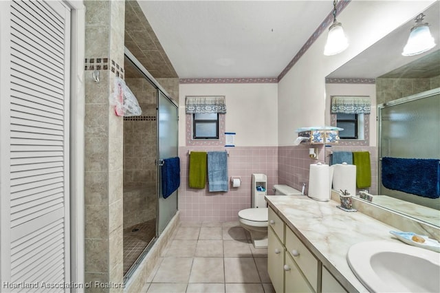 bathroom with tile patterned flooring, vanity, an enclosed shower, and tile walls