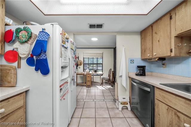 kitchen with backsplash, light tile patterned floors, stainless steel dishwasher, and white refrigerator with ice dispenser