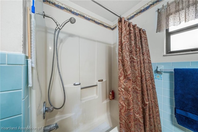 bathroom with shower / bathtub combination with curtain and tile walls