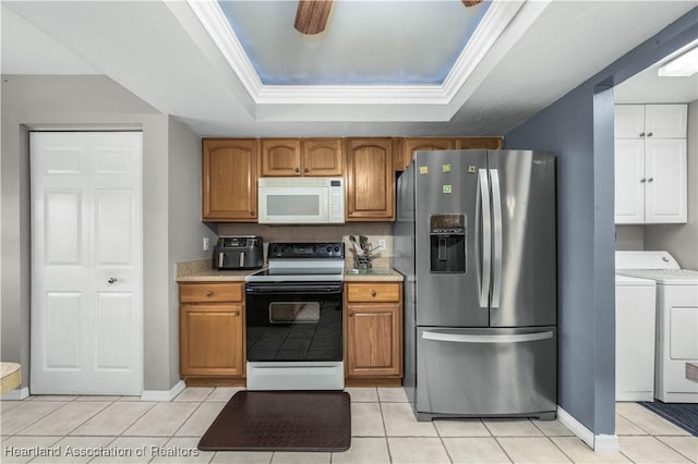 kitchen featuring stainless steel fridge with ice dispenser, electric range oven, ornamental molding, a tray ceiling, and washer and clothes dryer