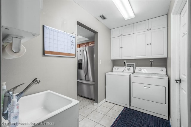 washroom with cabinets, washer and dryer, sink, and light tile patterned floors