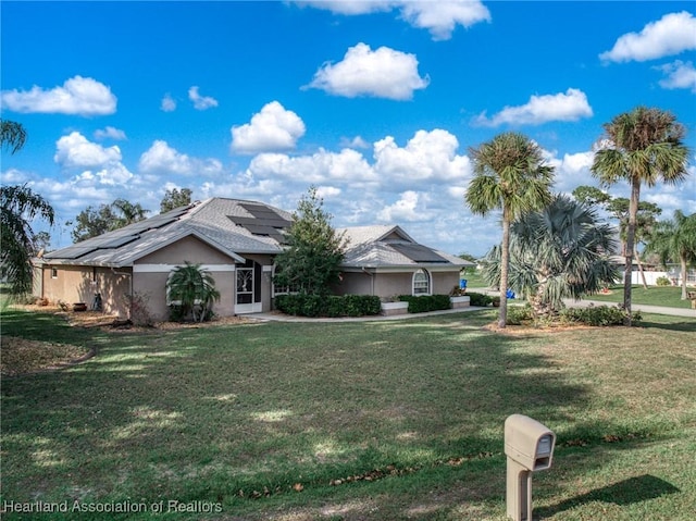 view of front of property featuring a front yard and solar panels