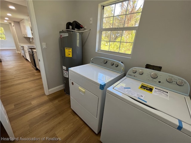 clothes washing area featuring independent washer and dryer, light wood-type flooring, and electric water heater