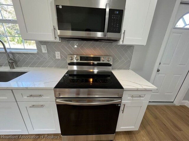 kitchen with light stone countertops, white cabinetry, sink, and appliances with stainless steel finishes