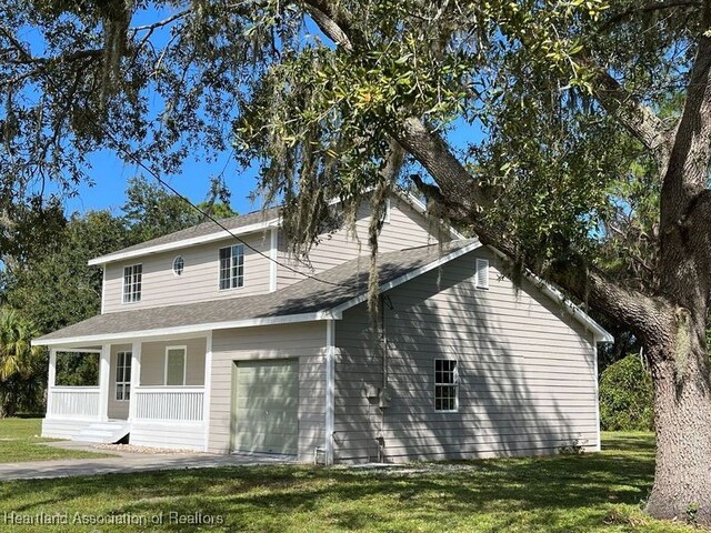 exterior space featuring a lawn, a garage, and covered porch