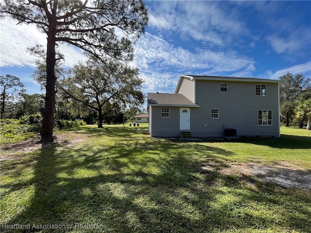 rear view of house with central AC and a lawn