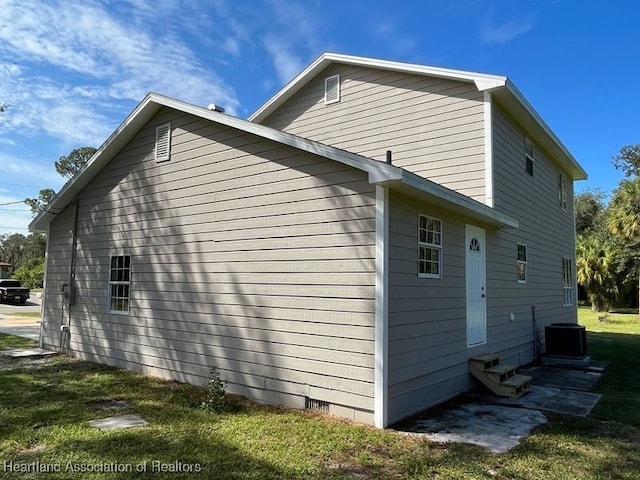 view of side of property featuring a lawn and cooling unit