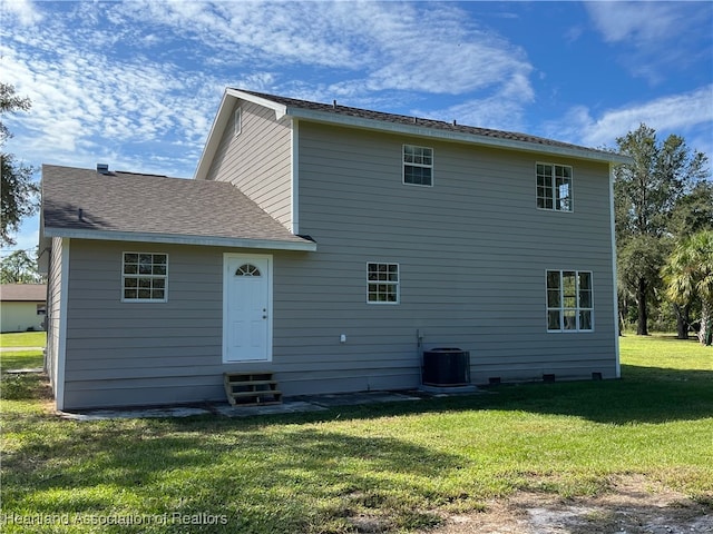 back of house featuring central AC unit and a lawn