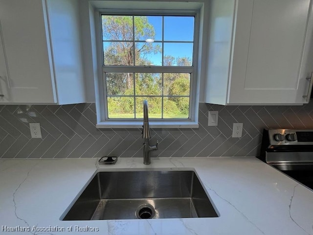 kitchen with decorative backsplash, white cabinetry, and light stone counters