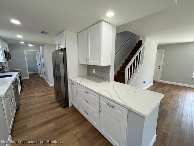 kitchen featuring white cabinets, stainless steel fridge, light stone countertops, tasteful backsplash, and kitchen peninsula