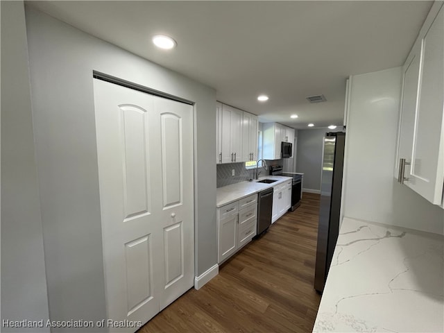 kitchen featuring backsplash, light stone counters, stainless steel appliances, sink, and white cabinets