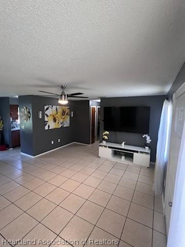 unfurnished living room featuring light tile patterned floors, a textured ceiling, and ceiling fan