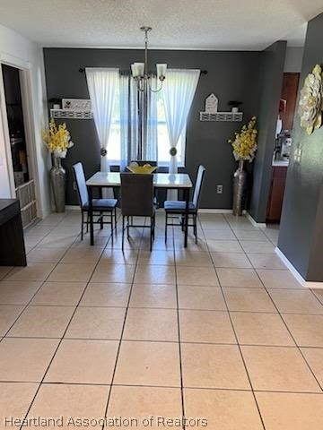 dining room with a chandelier, light tile patterned floors, and a textured ceiling