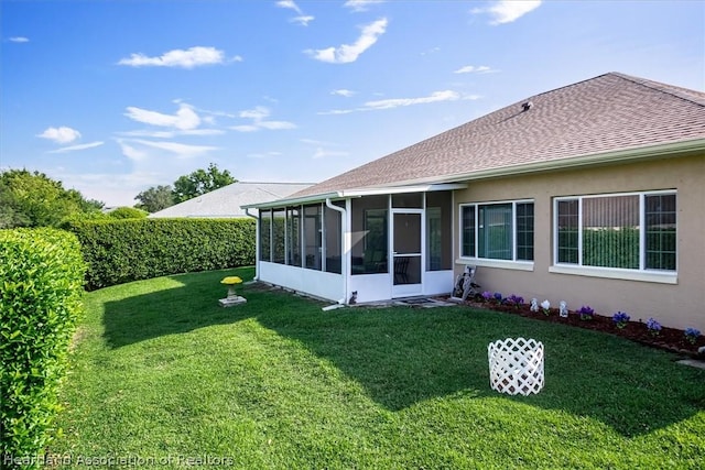 back of house featuring a lawn and a sunroom