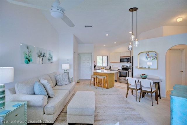 living area with recessed lighting, arched walkways, ceiling fan, and vaulted ceiling