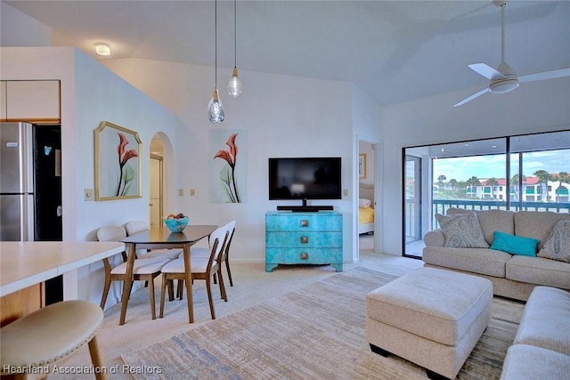 living room with arched walkways, light colored carpet, a ceiling fan, and vaulted ceiling