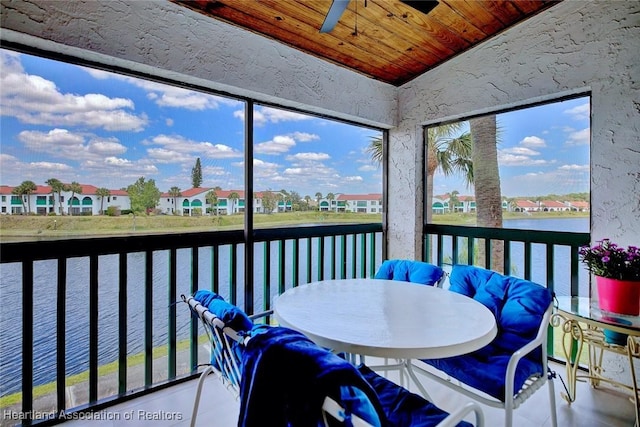 sunroom / solarium with a ceiling fan, lofted ceiling, a water view, wooden ceiling, and a residential view