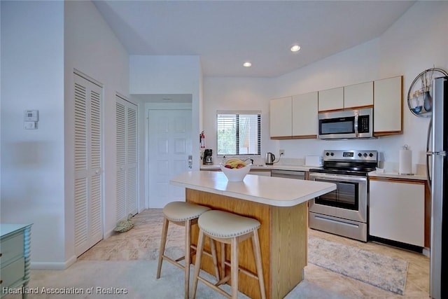 kitchen with a breakfast bar, recessed lighting, light countertops, appliances with stainless steel finishes, and a center island