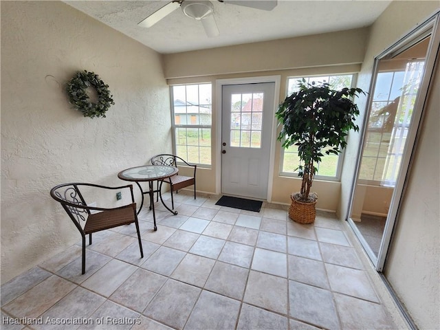 doorway with ceiling fan and light tile patterned flooring