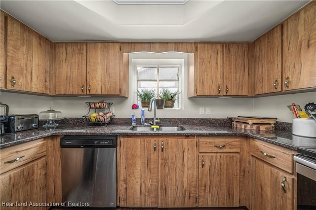 kitchen with dark stone counters, sink, a tray ceiling, and stainless steel appliances