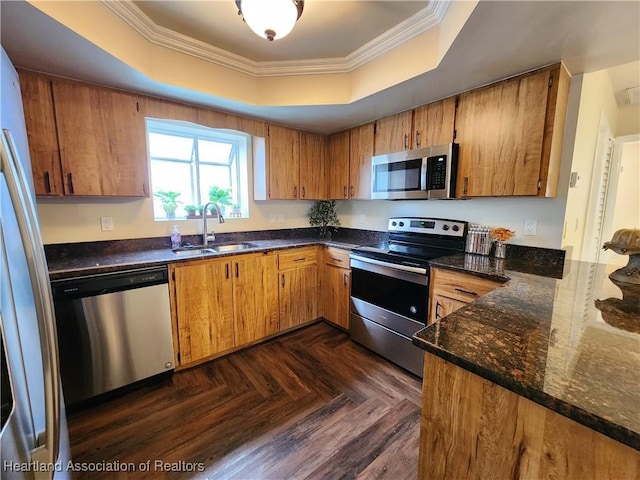 kitchen with dark parquet flooring, stainless steel appliances, a raised ceiling, and sink