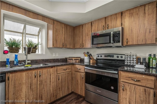 kitchen featuring dark hardwood / wood-style flooring, stainless steel appliances, dark stone countertops, and sink