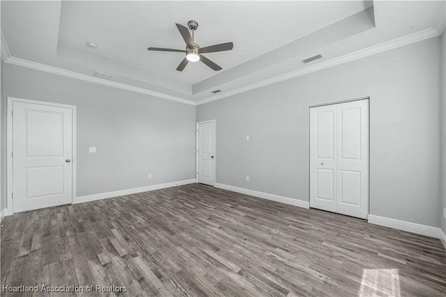 unfurnished room with a tray ceiling, ceiling fan, crown molding, and hardwood / wood-style flooring