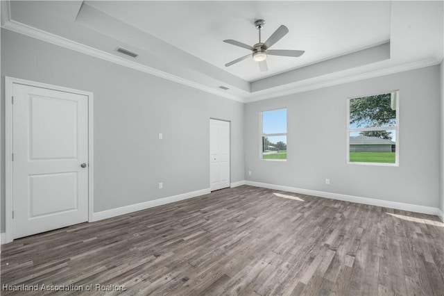 unfurnished room with a raised ceiling, ceiling fan, and wood-type flooring