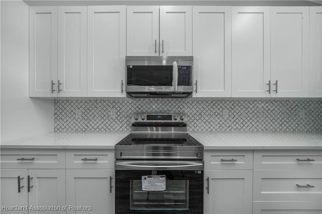 kitchen with decorative backsplash, white cabinetry, and stainless steel appliances