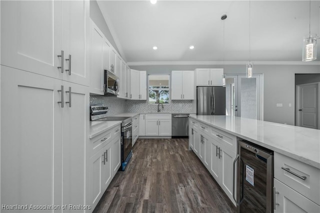 kitchen with hanging light fixtures, appliances with stainless steel finishes, white cabinetry, and beverage cooler