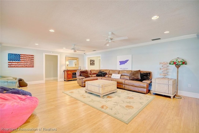 living room with a textured ceiling, hardwood / wood-style flooring, ceiling fan, and ornamental molding
