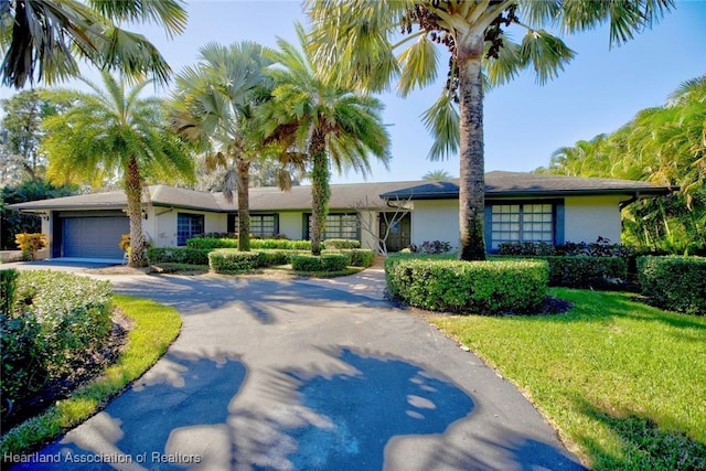 single story home featuring a garage and a front lawn