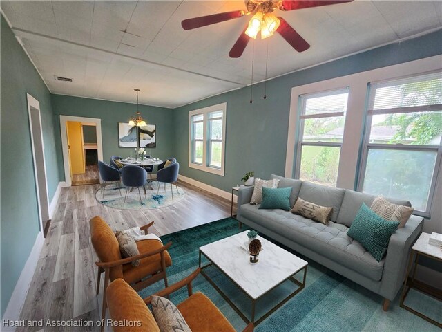 unfurnished dining area with ceiling fan with notable chandelier, light hardwood / wood-style flooring, and plenty of natural light