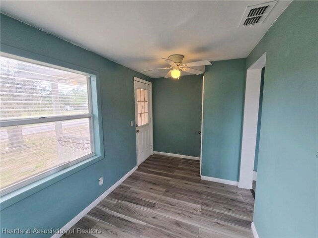 spare room with wood-type flooring and ceiling fan with notable chandelier