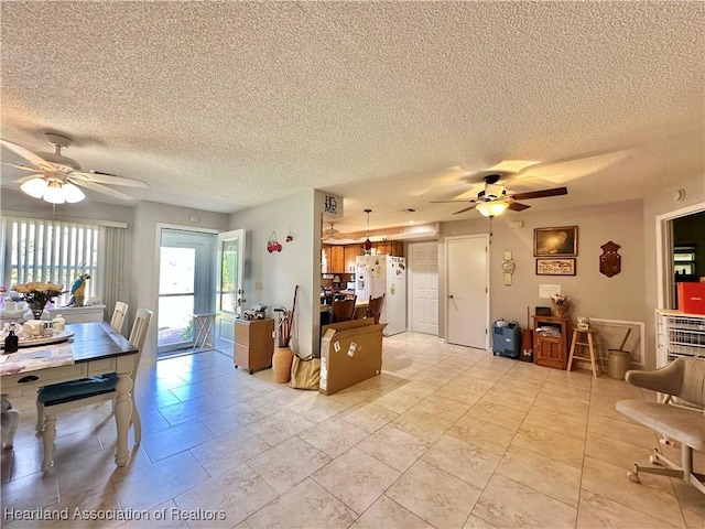 kitchen featuring white refrigerator with ice dispenser, pendant lighting, a textured ceiling, and ceiling fan