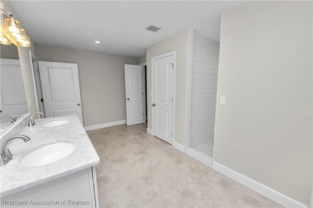 bathroom with a tile shower and vanity