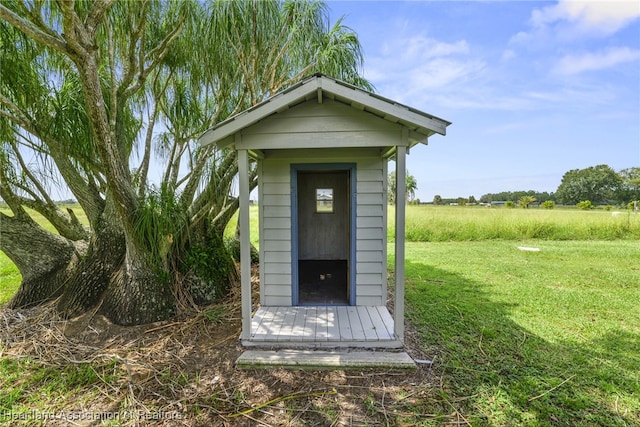 view of outbuilding with a lawn and a rural view