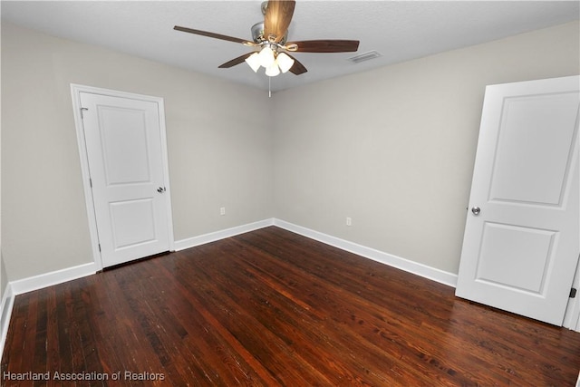 empty room with ceiling fan and dark hardwood / wood-style flooring