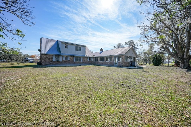 3150 Schontag Rd, Wauchula, FL 33873 - back of property with metal roof, brick siding, a yard, and a chimney