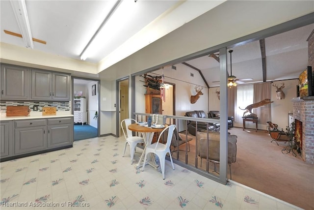 3150 Schontag Rd, Wauchula, FL 33873 - kitchen featuring tasteful backsplash, lofted ceiling, gray cabinetry, a ceiling fan, and a brick fireplace