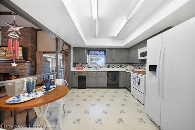 3150 Schontag Rd, Wauchula, FL 33873 - kitchen featuring gray cabinetry, white appliances, a fireplace, light countertops, and decorative backsplash