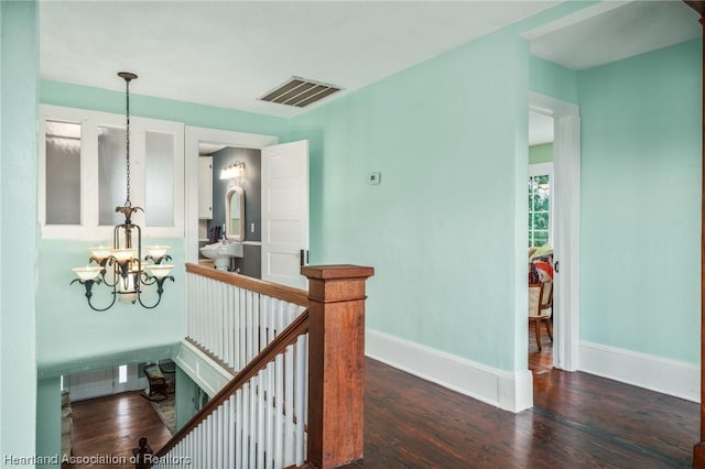 hall with dark hardwood / wood-style flooring and a notable chandelier