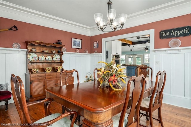 dining space with crown molding, light hardwood / wood-style floors, and ceiling fan with notable chandelier