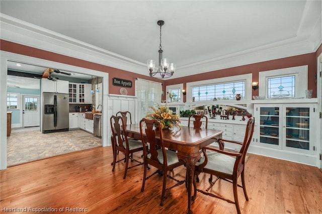 dining area with ceiling fan with notable chandelier, light hardwood / wood-style floors, crown molding, and sink