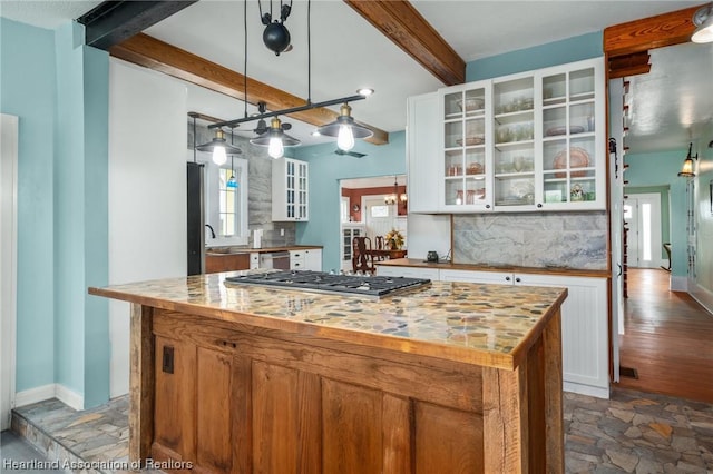 kitchen featuring beam ceiling, white cabinetry, a center island, hanging light fixtures, and stainless steel gas cooktop