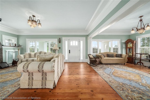 living room featuring a healthy amount of sunlight, ornamental molding, and a chandelier