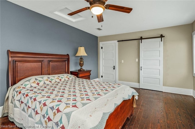 bedroom featuring a barn door, ceiling fan, and dark hardwood / wood-style floors